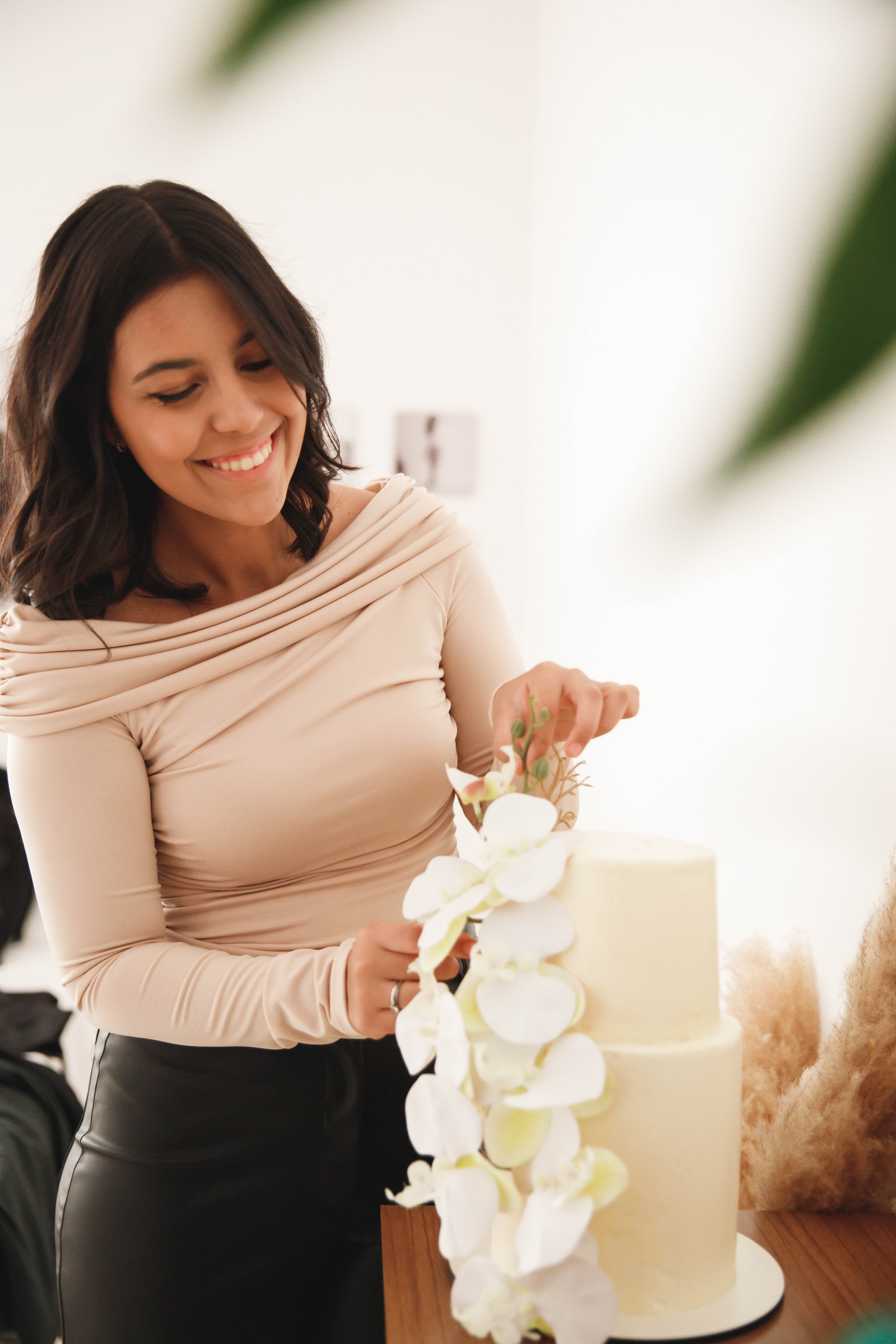 Confeiteira finalizando decoração de bolo com orquídeas
