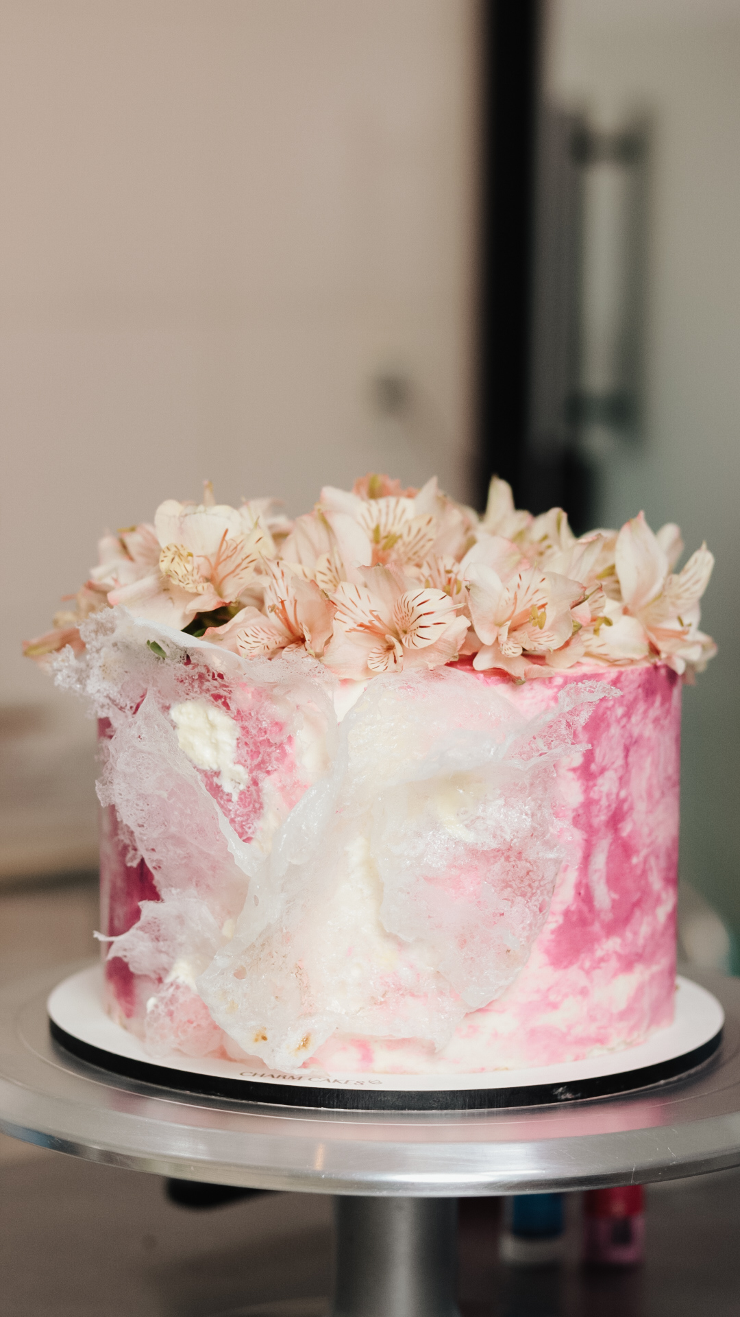 Bolo rosa com folha de ouro e flores naturais no topo