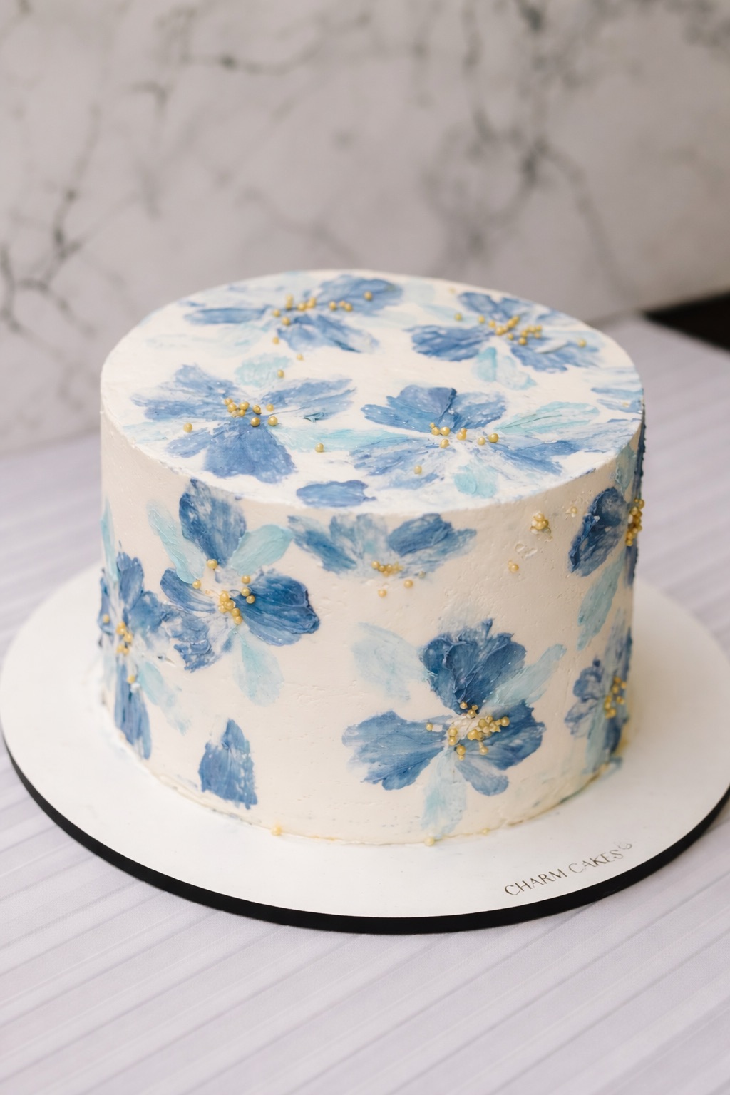 Bolo com flores pintadas à mão estilo aquarela azul e detalhes dourados